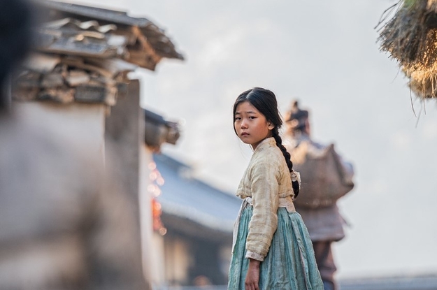 Una niña en un hanbok se encuentra al aire libre en Corea luciendo desesperada